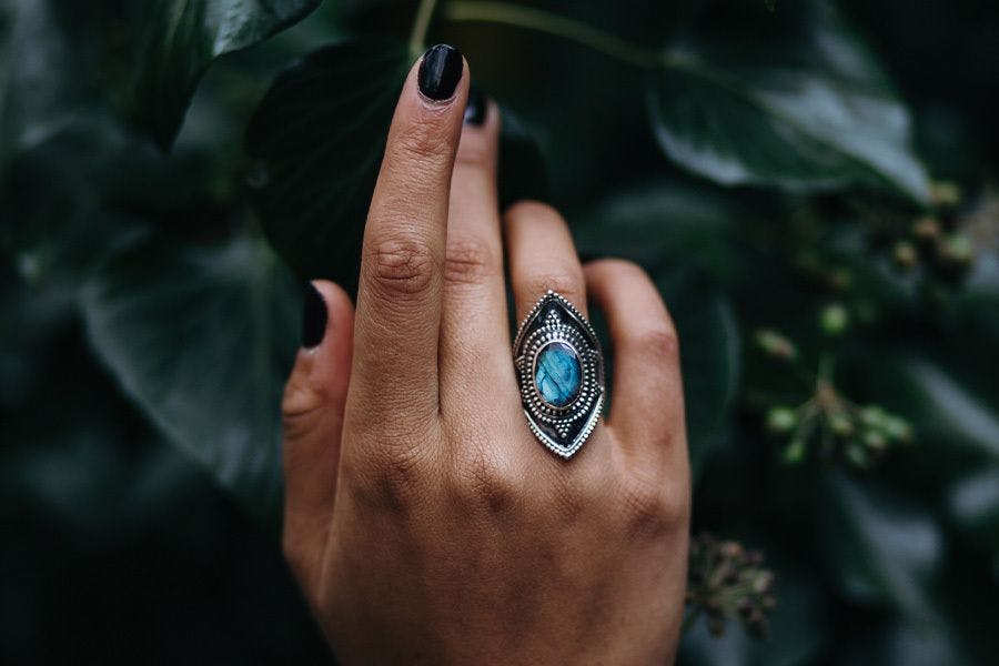 Hand met donkere nagellak en een grote blauwe ring