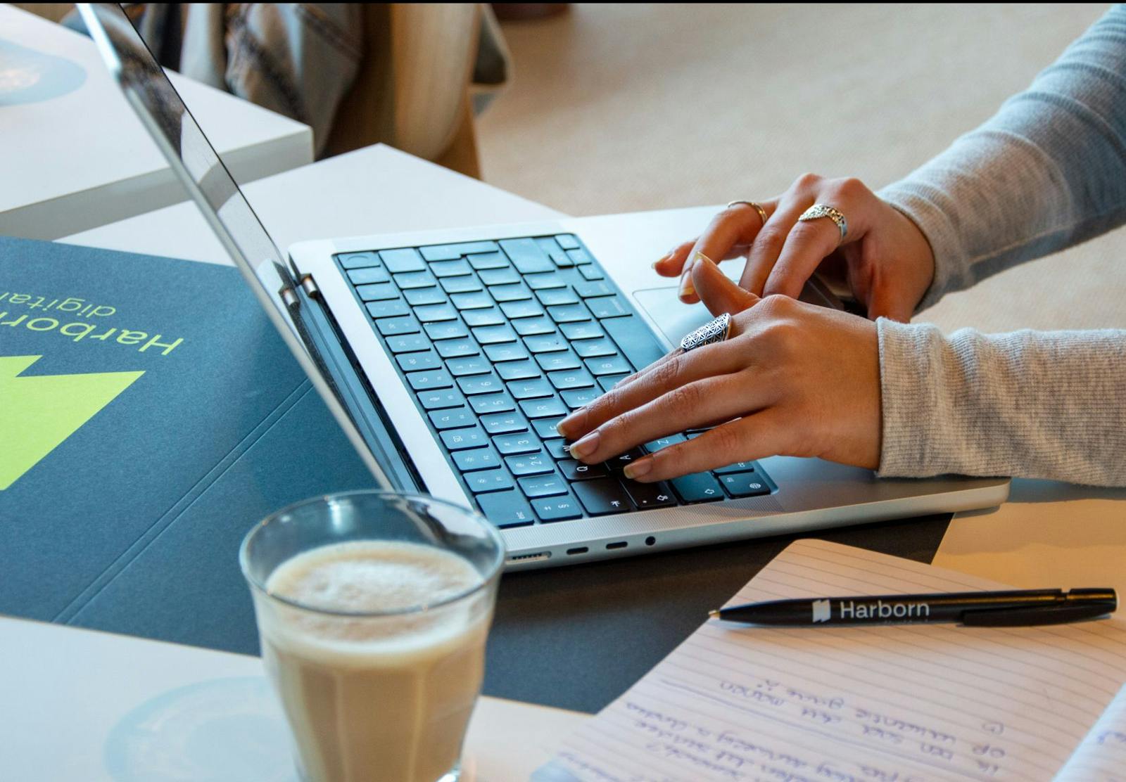 Digitale marketingprofessional werkt aan een laptop met analyses en strategie aantekeningen op het bureau, naast een kopje koffie.