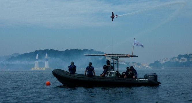 Foto van een boot op het water met een vliegtuig erboven