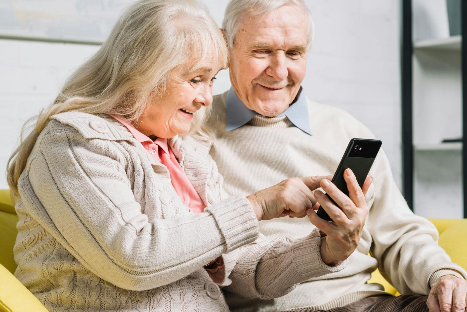 Twee senioren die op een mobiele telefoon kijken